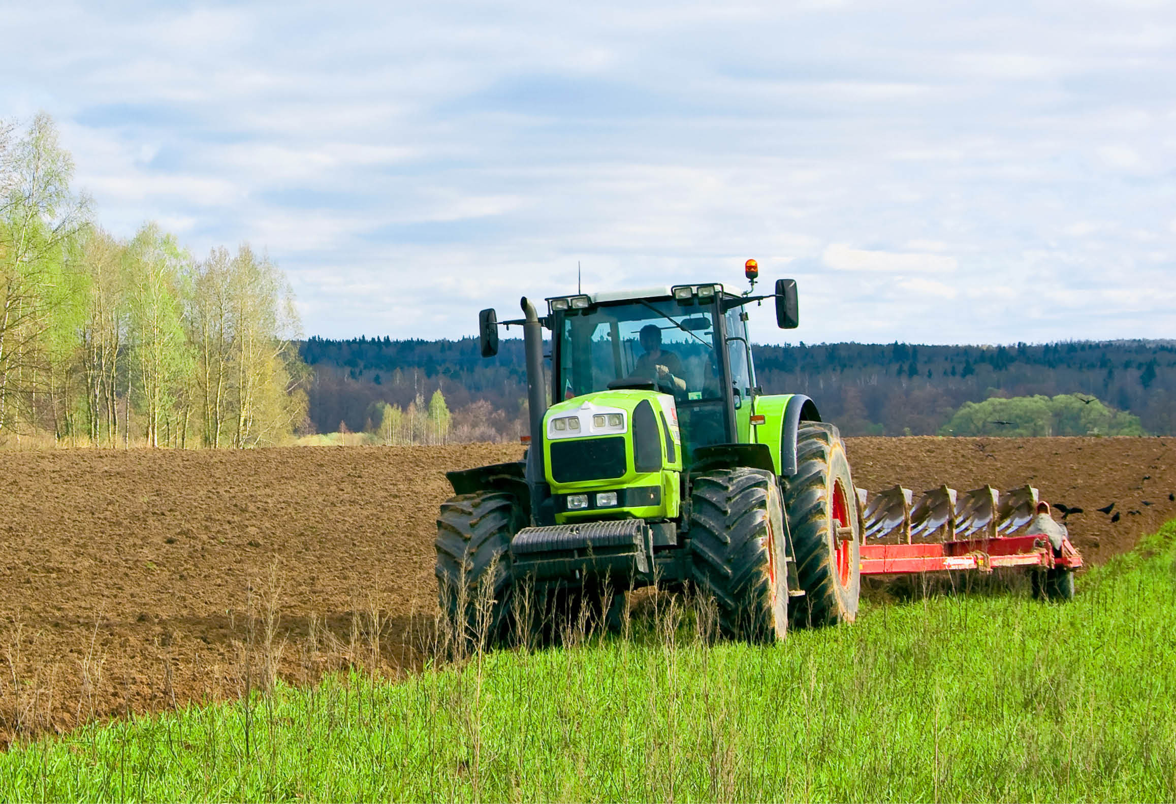 Lantbrukare som kör traktor och plöjer en åker